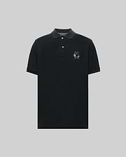 The Psycho Bunny MENS AUGUSTE PIQUE POLO SHIRT (MT0100051) is a black, short-sleeved collared polo with three buttons and an embroidered chenille bunny patch on the left chest, shown against a plain gray background. (5)