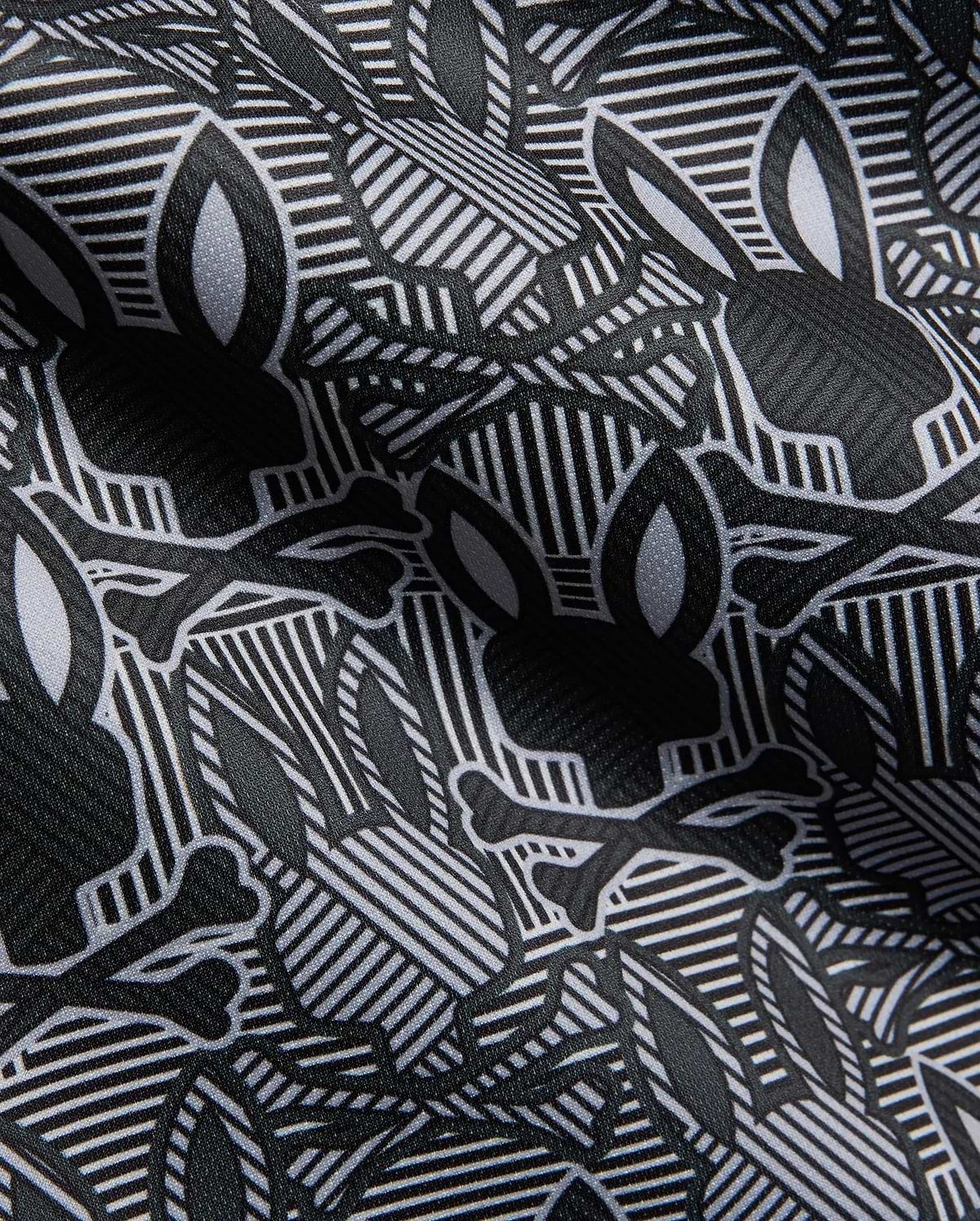 Mens Reeves All Over Bunny Sport Polo in black, white, and grey, featuring an all-over Psycho Bunny skull and crossbones print on a geometric striped performance fabric.