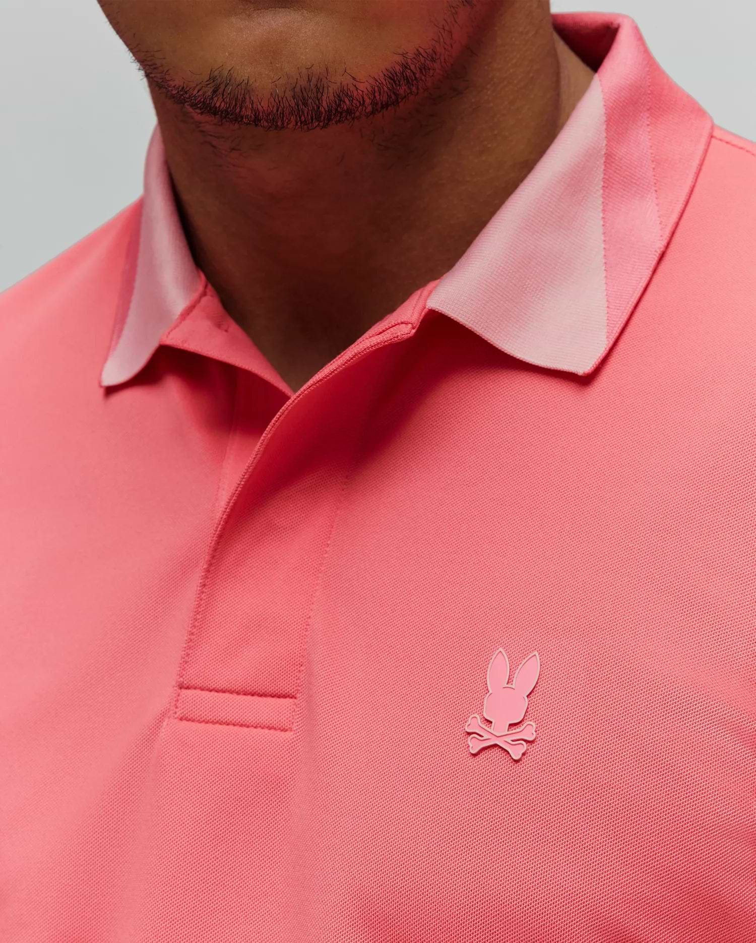 Mens Onyx Sport Polo in vibrant coral pique knit, featuring a lighter pink accent collar and a tonal embroidered Psycho Bunny skull logo on the left chest. (2)