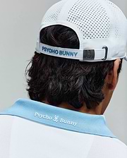 Mens Onyx Sport Polo in white pique with a light blue ribbed collar featuring white embroidered Psycho Bunny text and skull logo on the back, paired with a white perforated sport cap with light blue Psycho Bunny text and a metal bunny skull buckle. (3)