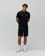Mens Ara Pique Polo in navy, classic fit, with white and orange striped collar and cuffs, featuring a small, colorful embroidered Psycho Bunny skull logo on the left chest, paired with navy shorts.