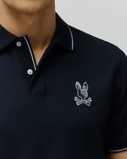Black Mens Olivier Pique Polo, classic fit, with white tipping on collar and sleeves, two white buttons, and a detailed embroidered black and white patterned Psycho Bunny skull logo on the left chest. (2)
