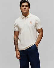 Mens Olivier Pique Polo in cream, featuring a classic fit, pique texture, orange tipping on the collar and cuffs, and an embroidered multi-color Psycho Bunny skull logo on the left chest. (3)