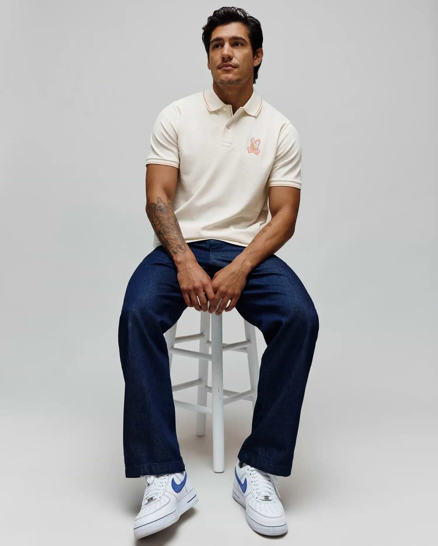 Mens Olivier Pique Polo, cream classic fit pique polo with orange tipping on collar and cuffs, featuring a small embroidered orange Psycho Bunny skull logo on the left chest. (1)