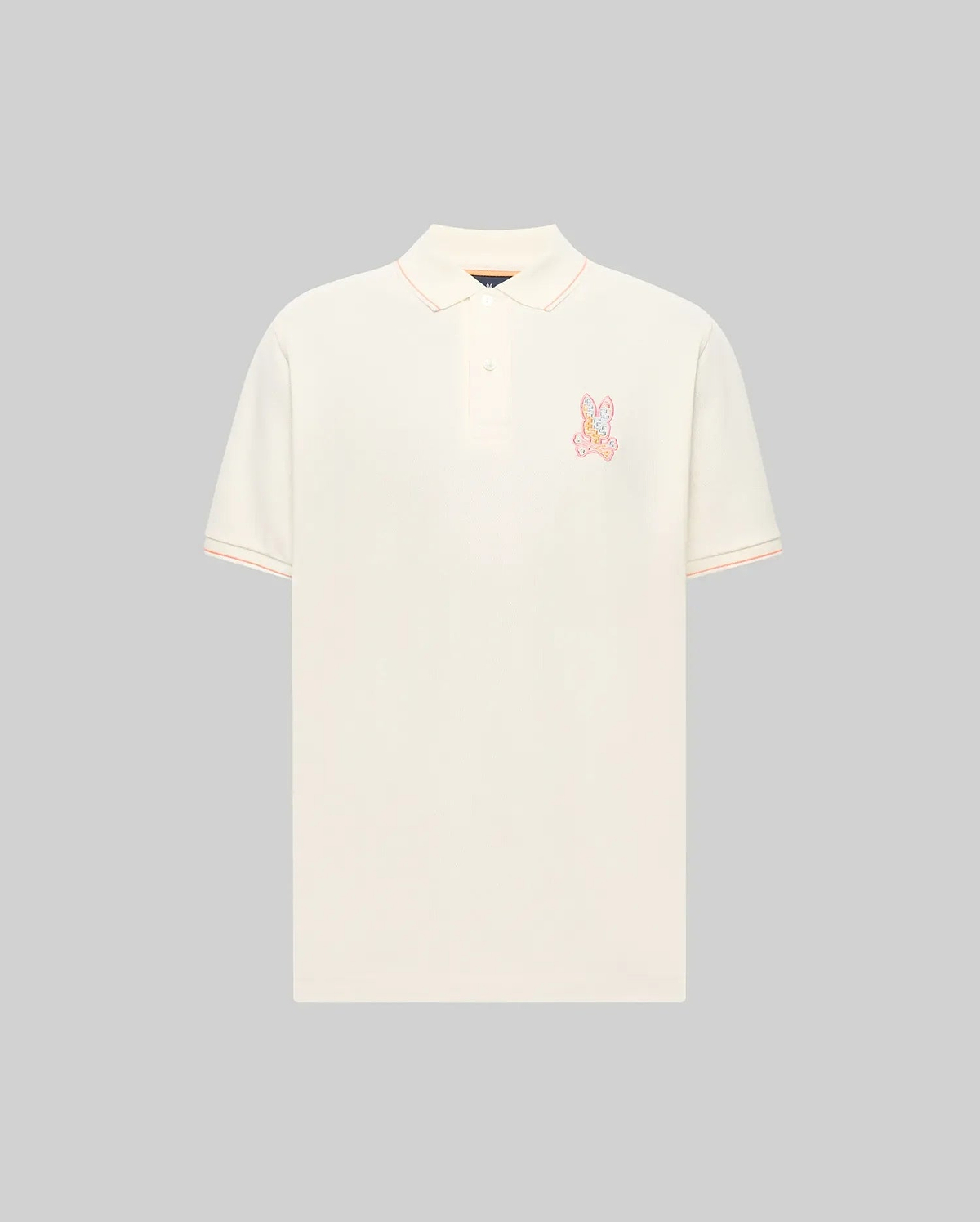Mens Olivier Pique Polo, a classic fit cream pique polo with peach tipping on the collar and sleeve cuffs, featuring a vibrant multi-color embroidered Psycho Bunny skull logo on the left chest. (4)