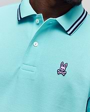 Mens Clark Pique Polo in aqua, featuring a classic fit, textured pique fabric, a ribbed collar with navy and pink stripes, and a small embroidered pink Psycho Bunny skull logo on the left chest. (2)