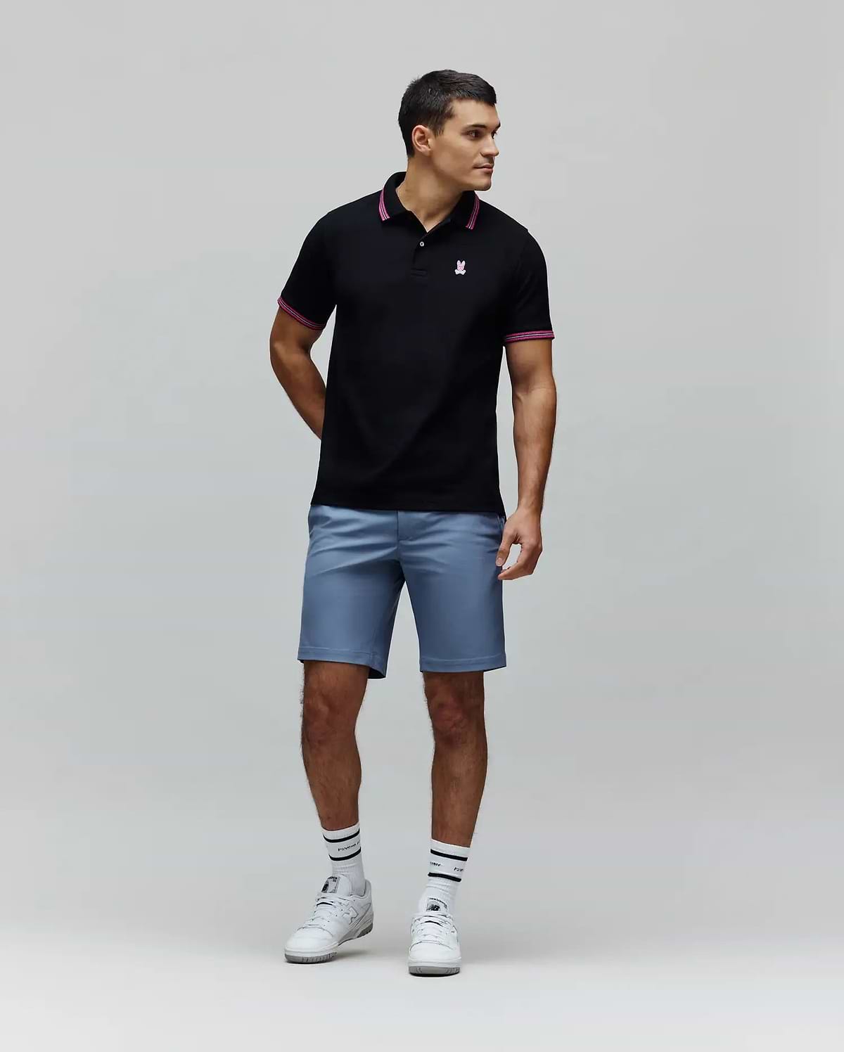 Black Mens Clark Pique Polo with classic fit, pique texture, featuring a small embroidered pink Psycho Bunny skull logo on the left chest, and pink striped collar and cuffs.