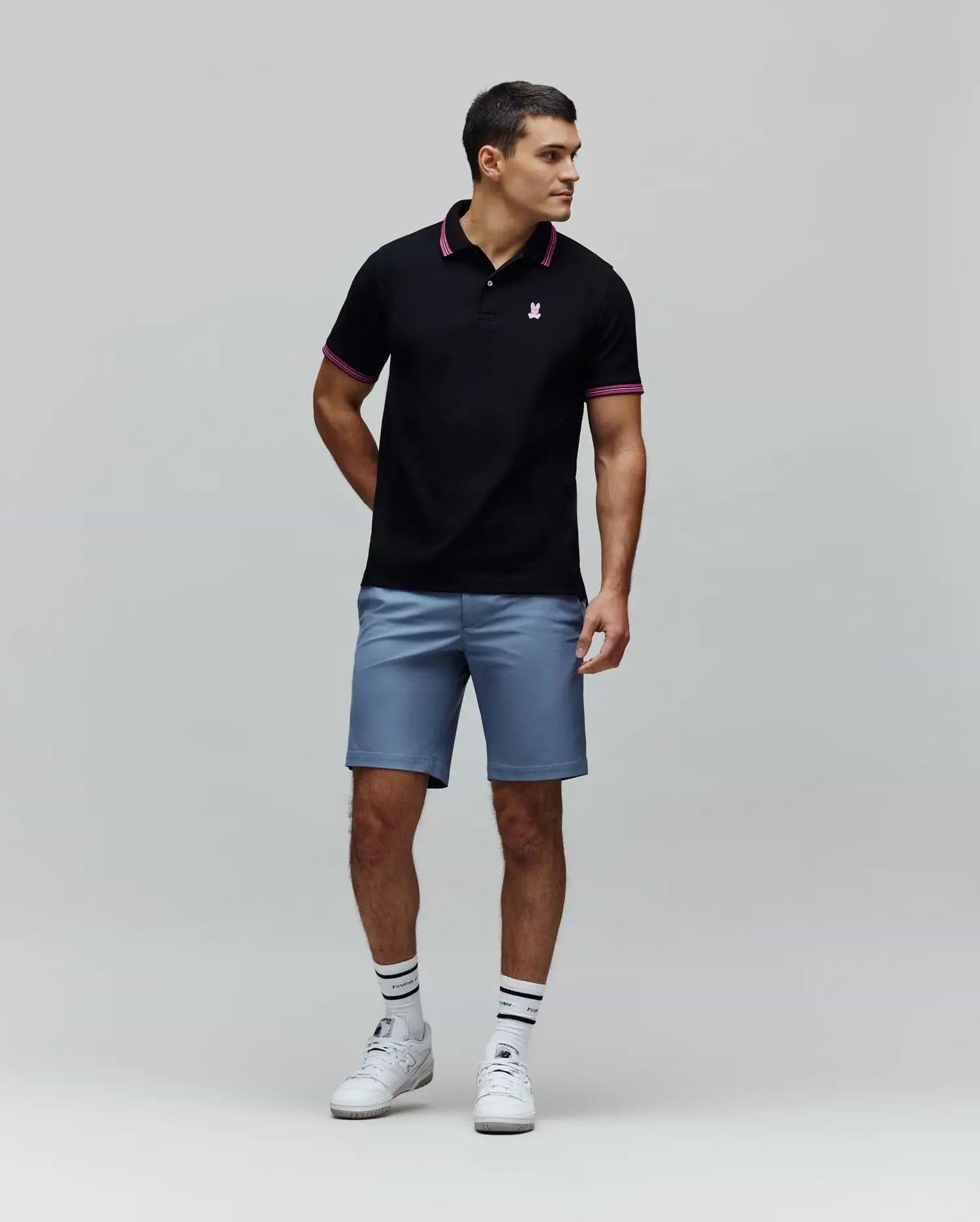 Black Mens Clark Pique Polo with classic fit, pique texture, featuring a small embroidered pink Psycho Bunny skull logo on the left chest, and pink striped collar and cuffs.