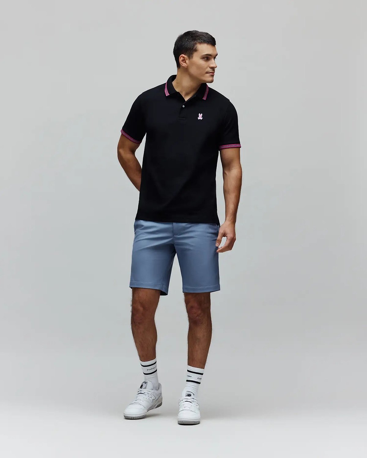 Black Mens Clark Pique Polo with classic fit, pique texture, featuring a small embroidered pink Psycho Bunny skull logo on the left chest, and pink striped collar and cuffs.