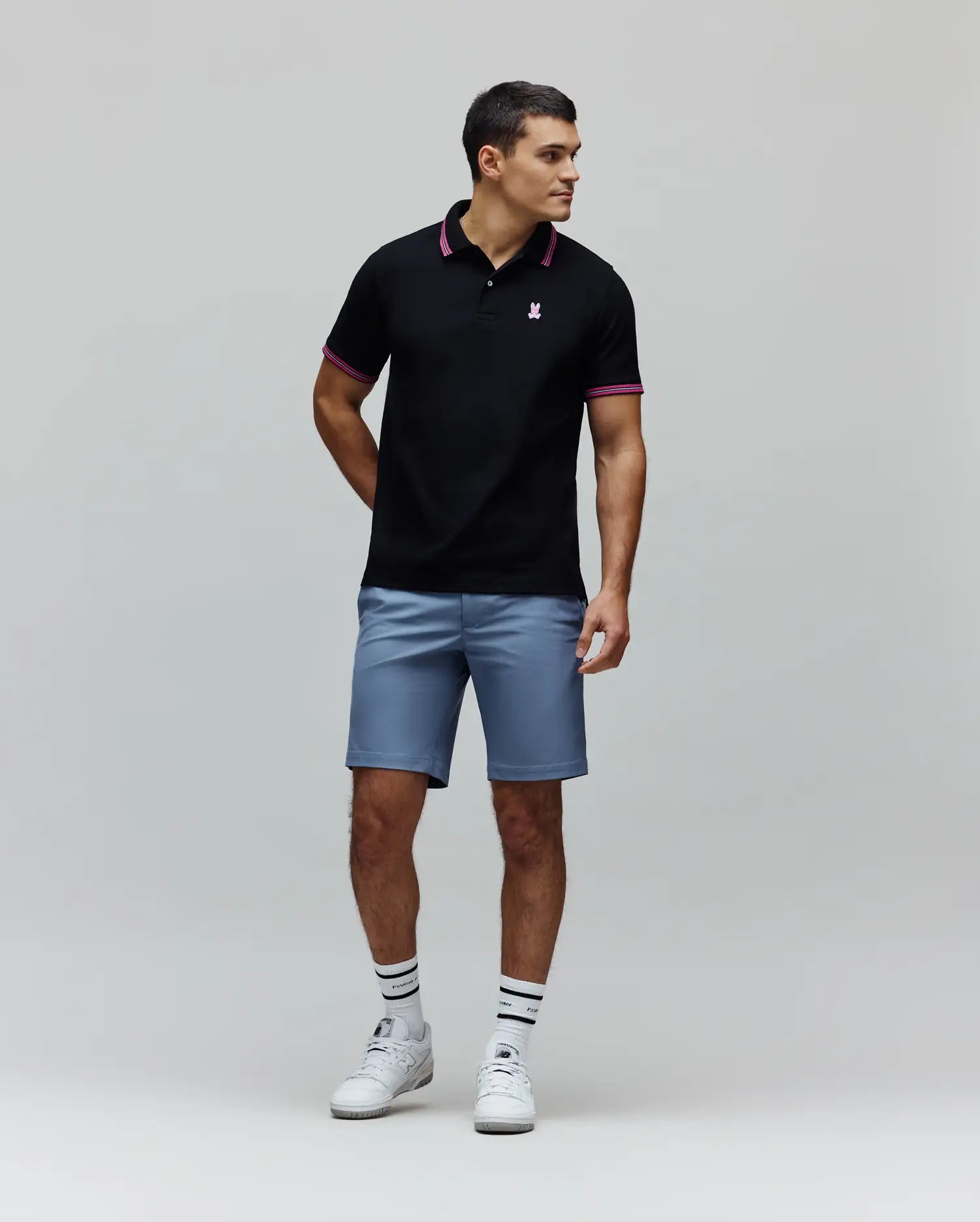 Black Mens Clark Pique Polo with classic fit, pique texture, featuring a small embroidered pink Psycho Bunny skull logo on the left chest, and pink striped collar and cuffs.