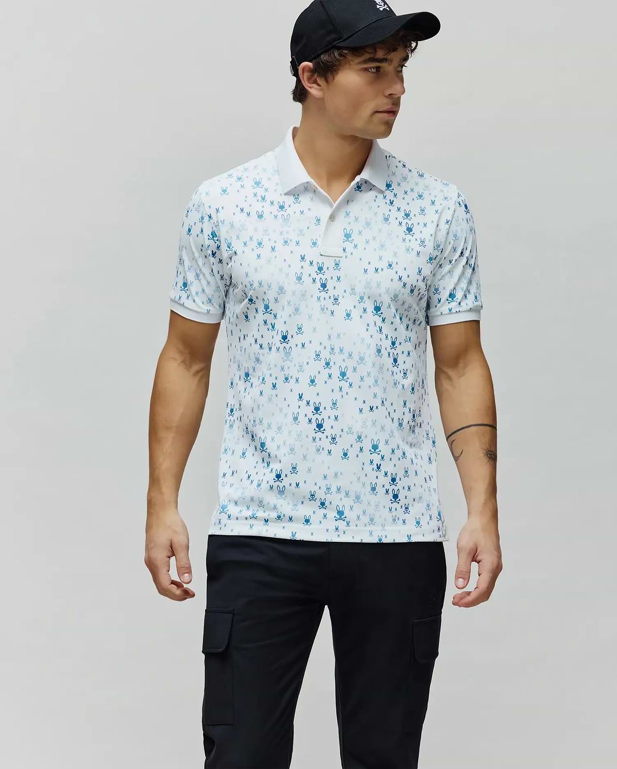 Mens Nev Sport Polo, white premium performance jersey with an all-over gradient blue iconic Psycho Bunny skull logo print, classic fit, white collar and cuffs.