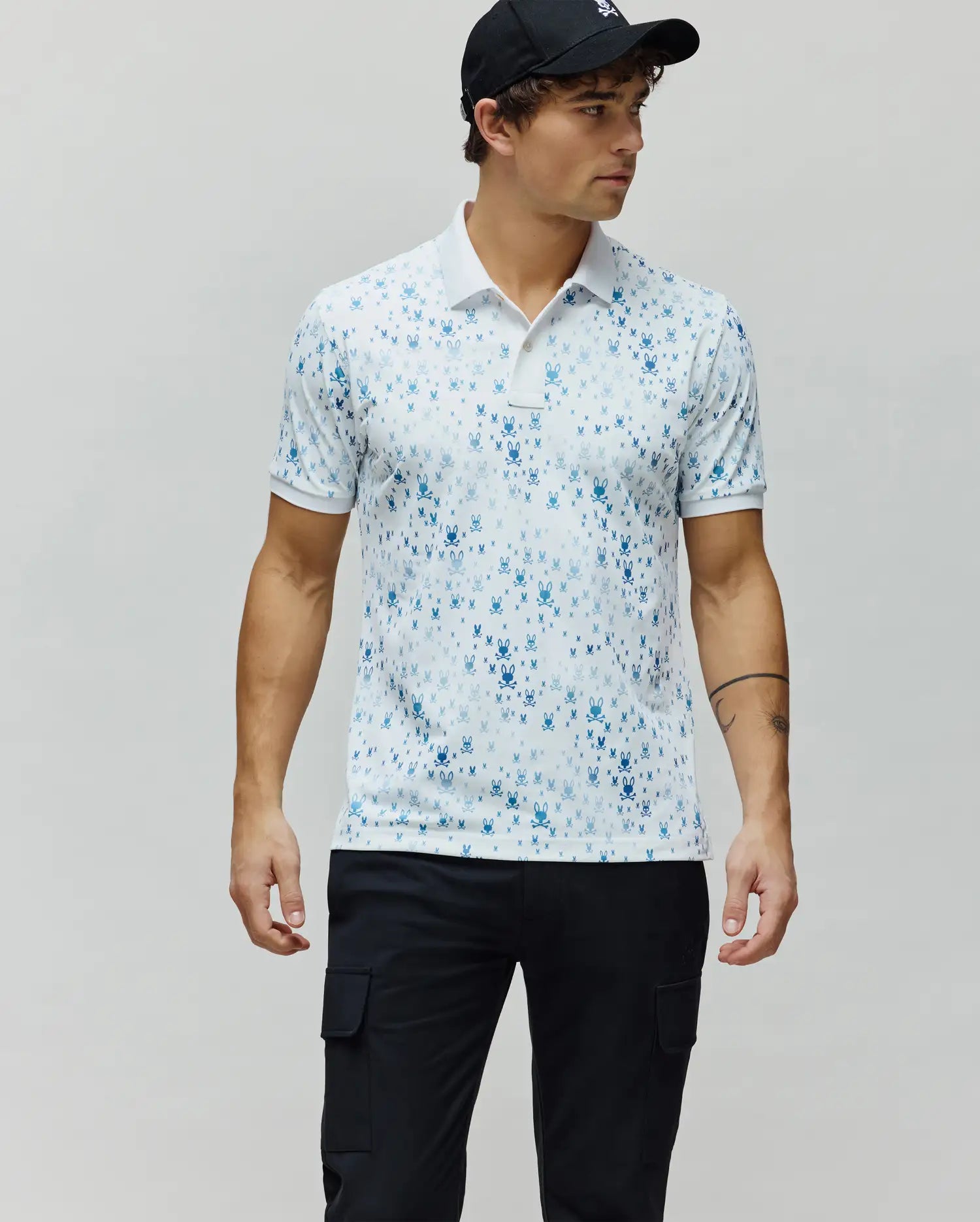 Mens Nev Sport Polo, white premium performance jersey with an all-over gradient blue iconic Psycho Bunny skull logo print, classic fit, white collar and cuffs.