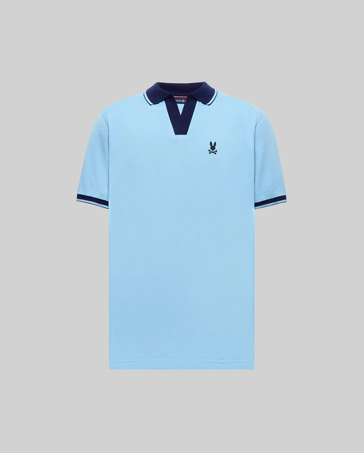Mens Christiano Pique Polo, light blue pique with navy V-neck collar, white stripe detail, ribbed cuffs with navy and white trim, and an embroidered navy bunny skull logo on left chest. (4)