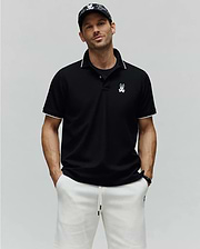 Mens Aram Pique Polo, a black classic fit pique knit polo shirt with white contrast tipping on the collar and sleeve cuffs, featuring an embroidered white Psycho Bunny skull logo on the left chest. (1)
