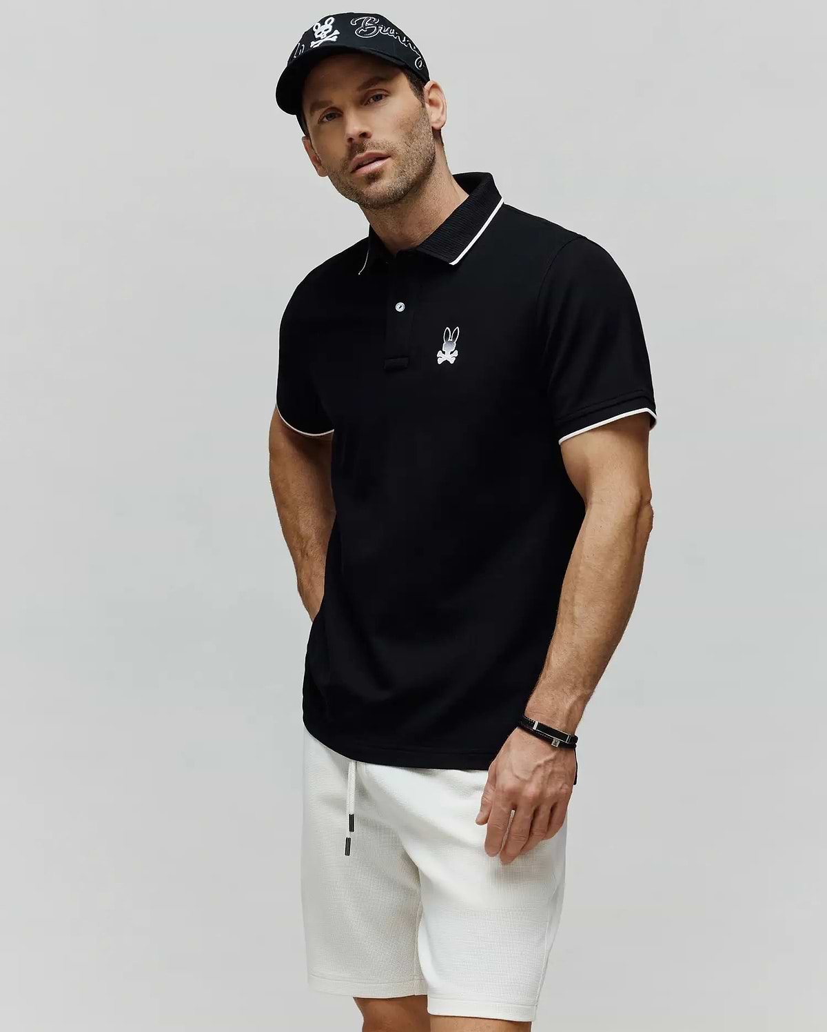 Black Mens Aram Pique Polo with white tipping on the collar and cuffs, featuring a two-button placket and an embroidered white Psycho Bunny skull logo on the left chest. (3)