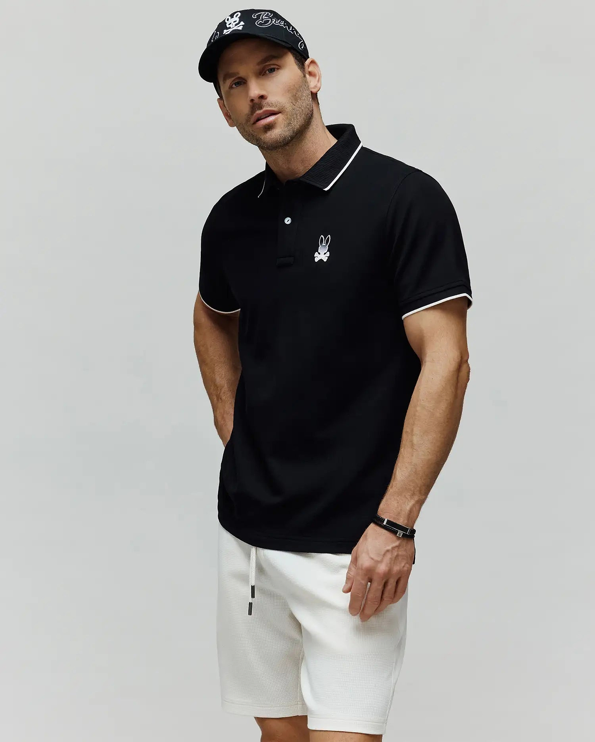 Black Mens Aram Pique Polo with white tipping on the collar and cuffs, featuring a two-button placket and an embroidered white Psycho Bunny skull logo on the left chest. (3)