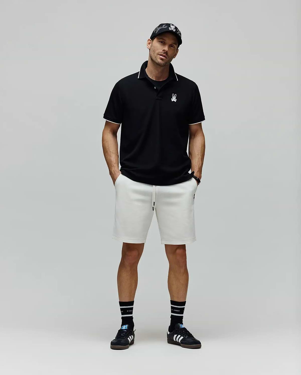Black Mens Aram Pique Polo with white tipping on the collar and cuffs, featuring a small white embroidered Psycho Bunny skull logo on the left chest, in a classic fit. (4)