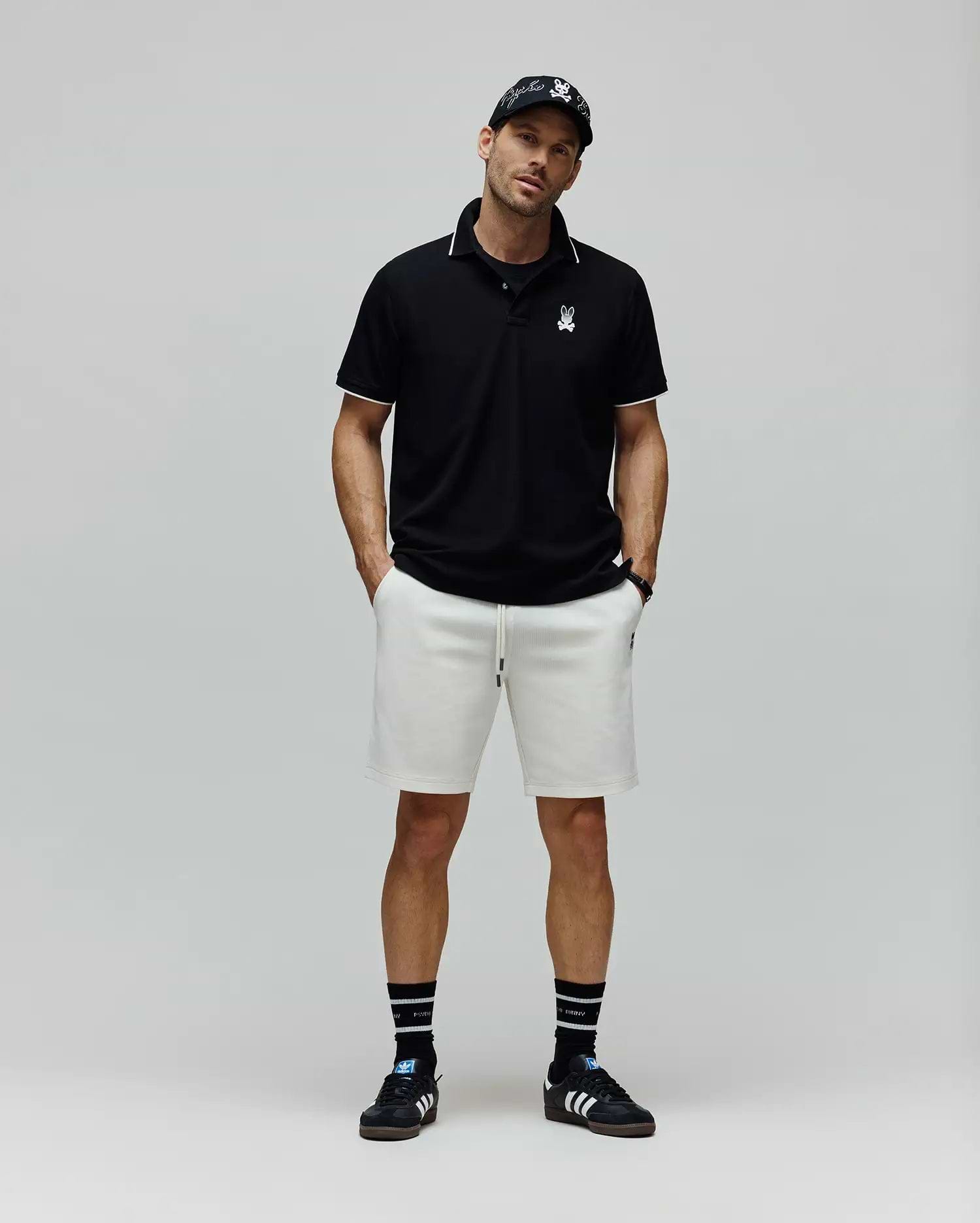 Black Mens Aram Pique Polo with white tipping on the collar and cuffs, featuring a small white embroidered Psycho Bunny skull logo on the left chest, in a classic fit. (4)