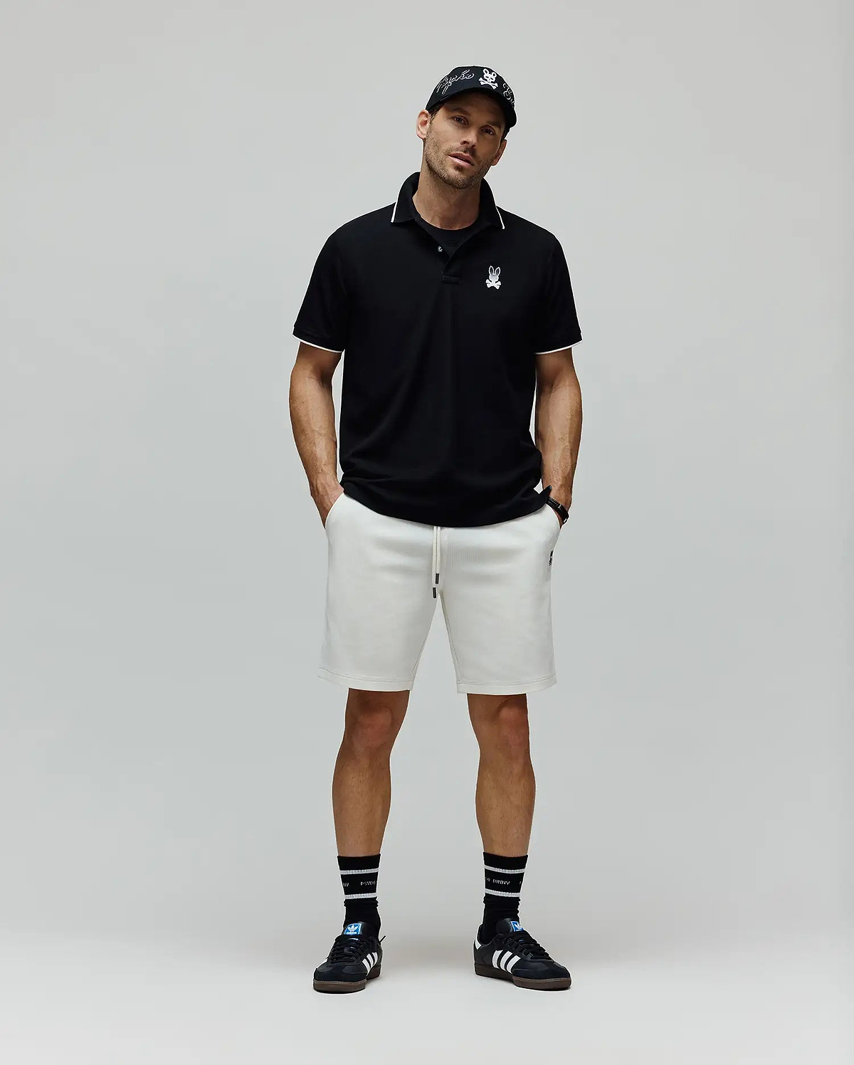 Black Mens Aram Pique Polo with white tipping on the collar and cuffs, featuring a small white embroidered Psycho Bunny skull logo on the left chest, in a classic fit. (4)