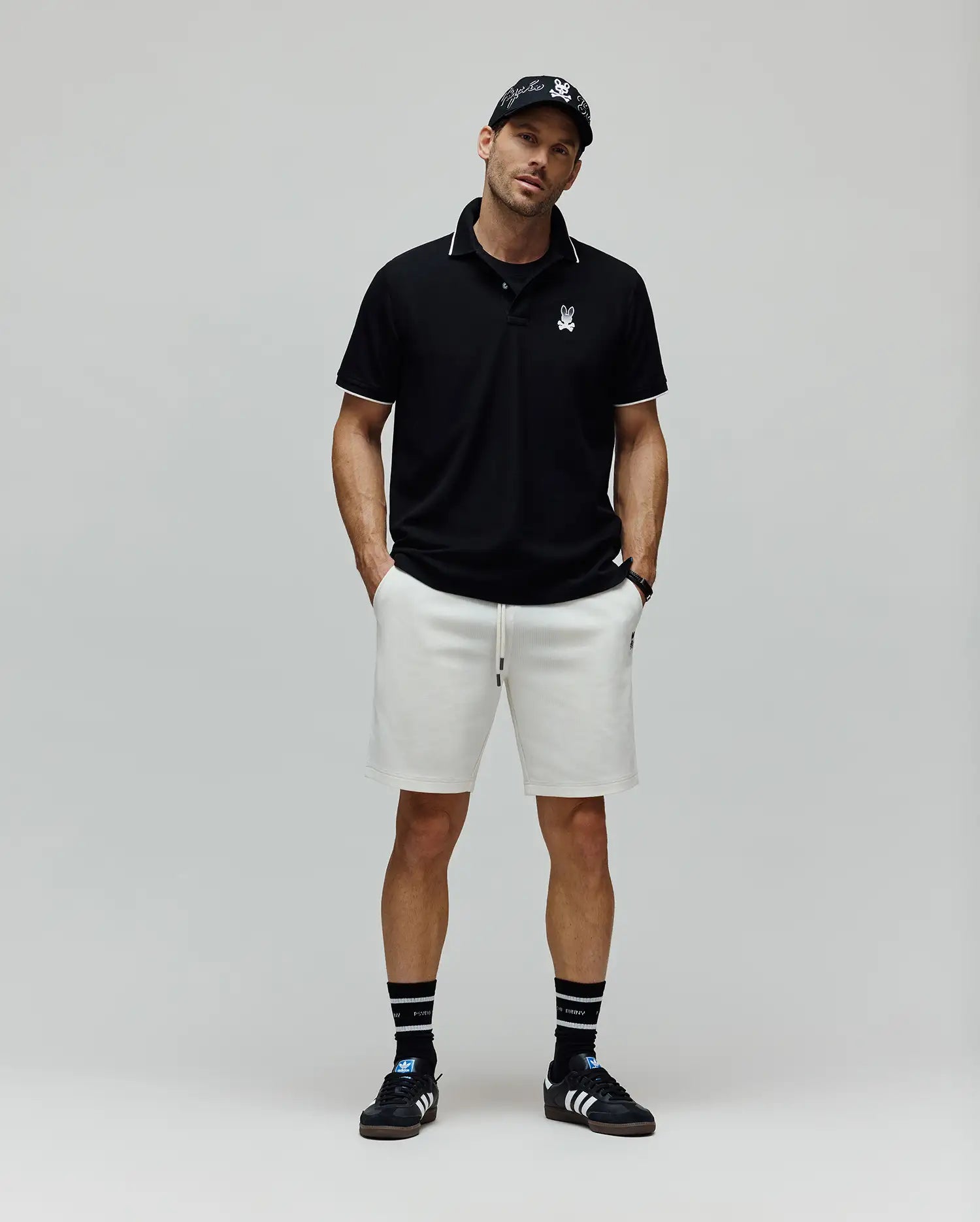 Black Mens Aram Pique Polo with white tipping on the collar and cuffs, featuring a small white embroidered Psycho Bunny skull logo on the left chest, in a classic fit. (4)