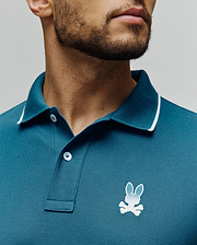 Mens Aram Pique Polo in teal, classic fit, pique knit, with a ribbed collar featuring white tipping, two white buttons, and a small embroidered white to light blue gradient Psycho Bunny skull logo on the left chest. (3)