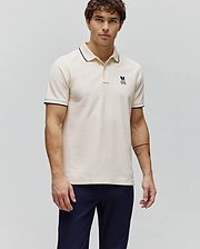Mens Aram Pique Polo in cream, featuring a classic fit, textured pique fabric, navy blue tipping on the collar and sleeve cuffs, and a small embroidered Psycho Bunny skull logo on the left chest. (3)