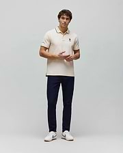Mens Aram Pique Polo, a cream classic fit pique polo with navy blue tipped collar and cuffs, featuring a small embroidered navy blue Psycho Bunny skull logo on the left chest. (4)