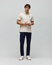 Mens Aram Pique Polo, a cream classic fit pique polo with navy blue tipped collar and cuffs, featuring a small embroidered navy blue Psycho Bunny skull logo on the left chest. (4)
