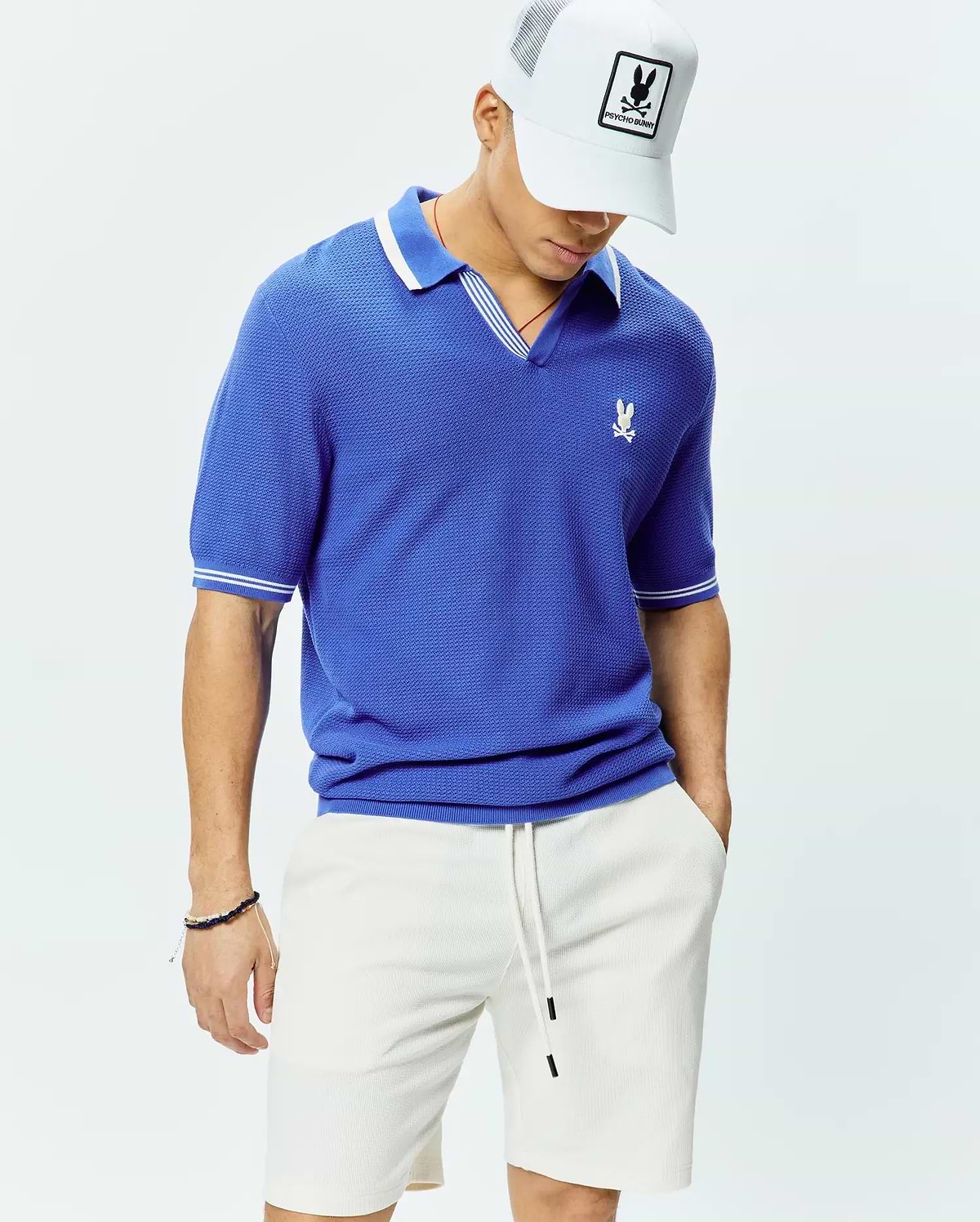 Mens Innis Polo, a royal blue classic fit pique knit polo with a V-neck, white striped collar, white striped sleeve cuffs, and a small embroidered white Psycho Bunny skull logo on the left chest. (3)