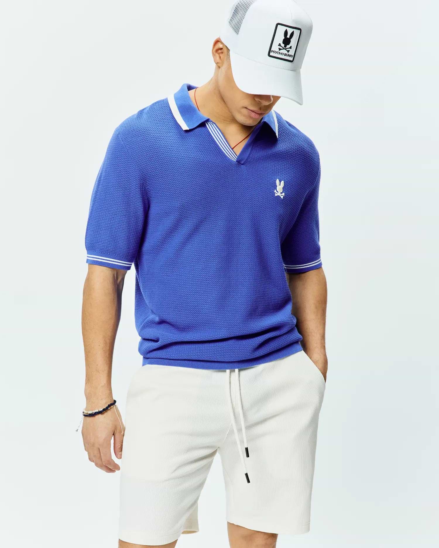 Mens Innis Polo, a royal blue classic fit pique knit polo with a V-neck, white striped collar, white striped sleeve cuffs, and a small embroidered white Psycho Bunny skull logo on the left chest. (3)