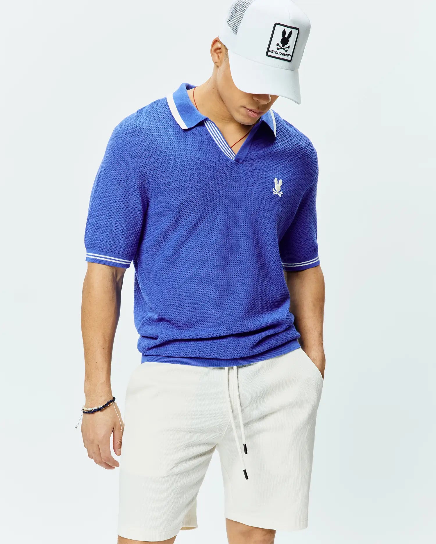 Mens Innis Polo, a royal blue classic fit pique knit polo with a V-neck, white striped collar, white striped sleeve cuffs, and a small embroidered white Psycho Bunny skull logo on the left chest. (3)