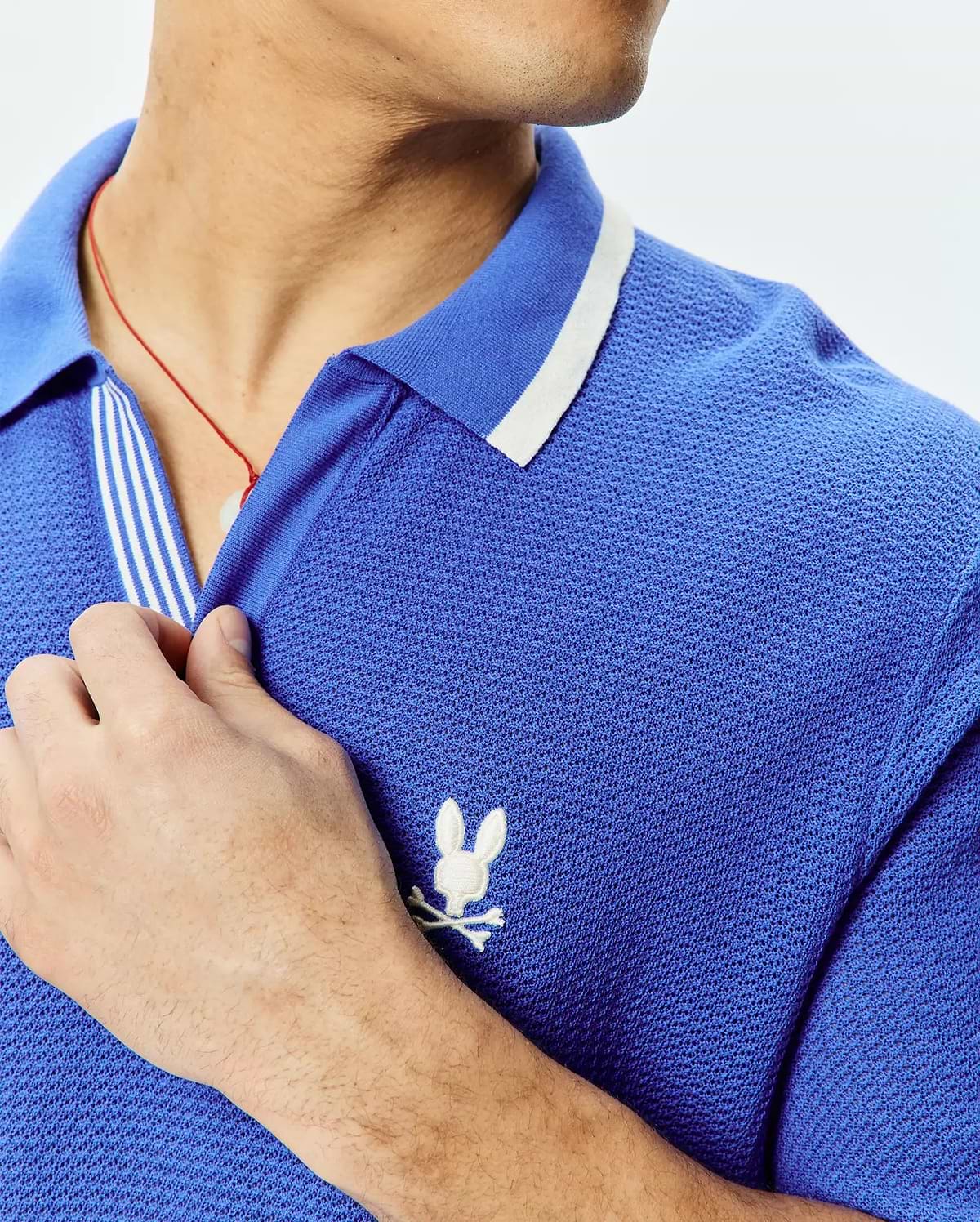 Mens Innis Polo, vibrant blue pique knit polo shirt with a classic fit, featuring a white striped collar, striped placket, and a small white embroidered Psycho Bunny skull logo on the left chest. (2)