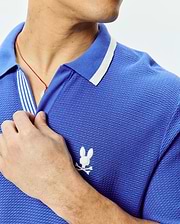 Mens Innis Polo, vibrant blue pique knit polo shirt with a classic fit, featuring a white striped collar, striped placket, and a small white embroidered Psycho Bunny skull logo on the left chest. (2)