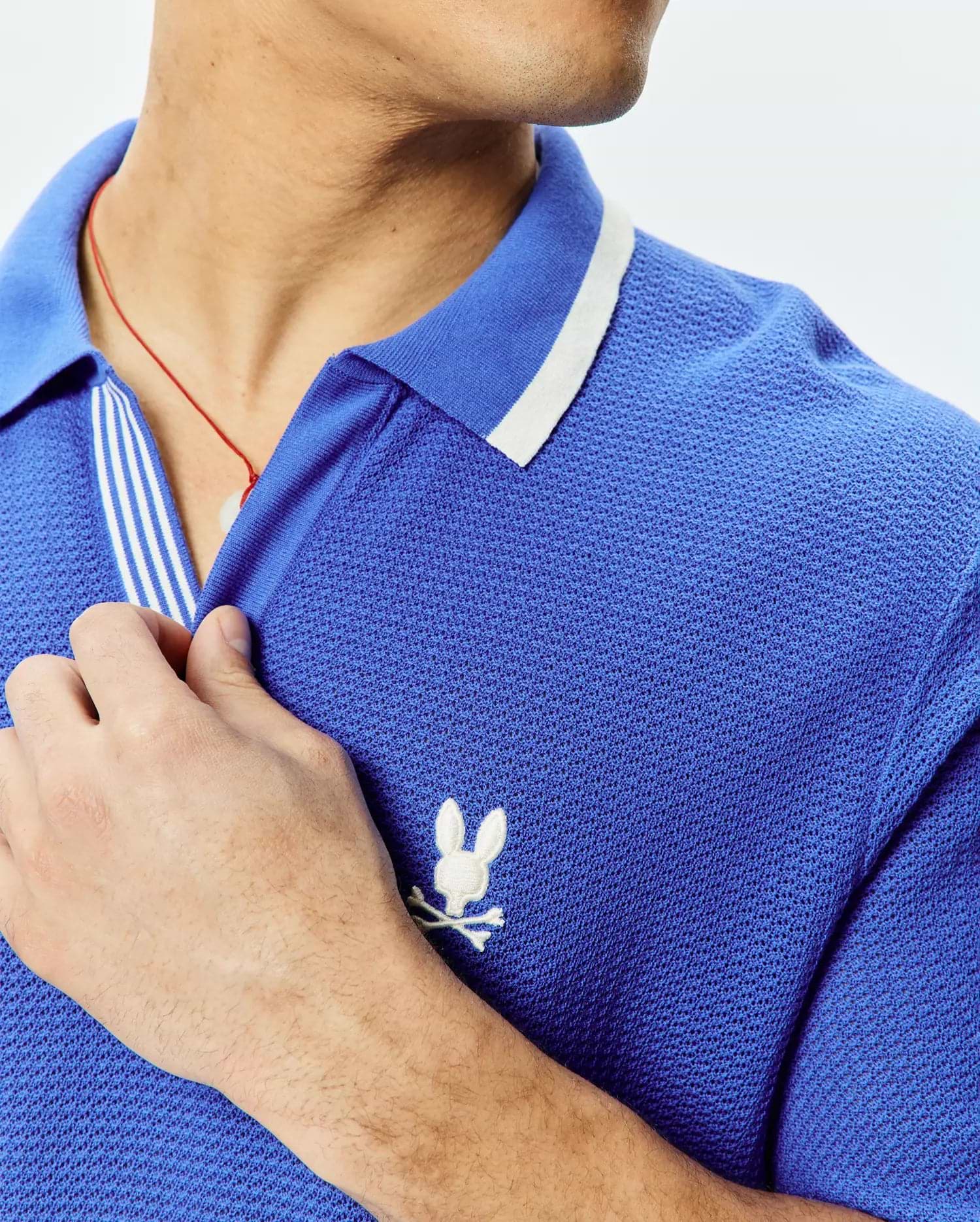Mens Innis Polo, vibrant blue pique knit polo shirt with a classic fit, featuring a white striped collar, striped placket, and a small white embroidered Psycho Bunny skull logo on the left chest. (2)