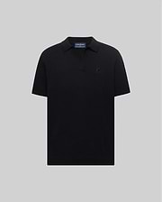 Mens Devon Knit Polo, a black classic fit polo in textured knit fabric with an open collar and a small, tonal black embroidered Psycho Bunny skull logo on the left chest.