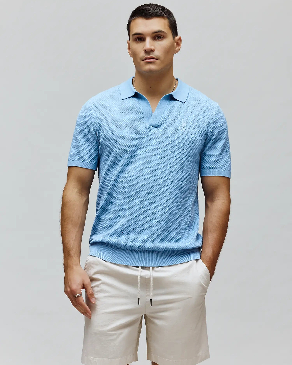 Mens Devon Knit Polo, sky blue textured knit polo shirt with an open spread collar, classic fit, and a small white embroidered Psycho Bunny skull logo on the left chest.