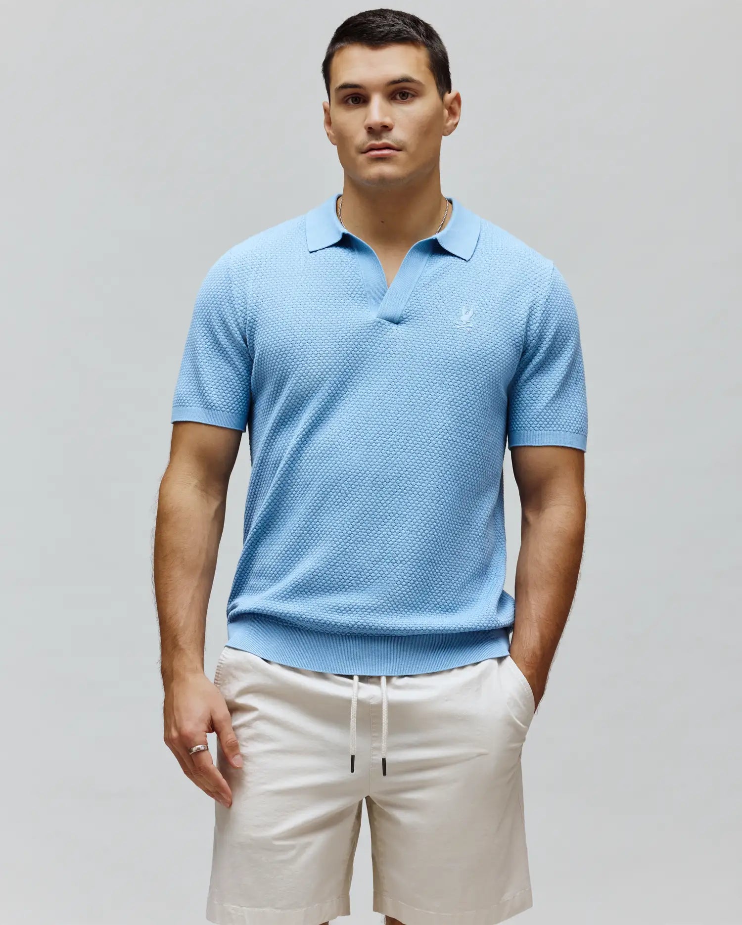 Mens Devon Knit Polo, sky blue textured knit polo shirt with an open spread collar, classic fit, and a small white embroidered Psycho Bunny skull logo on the left chest.