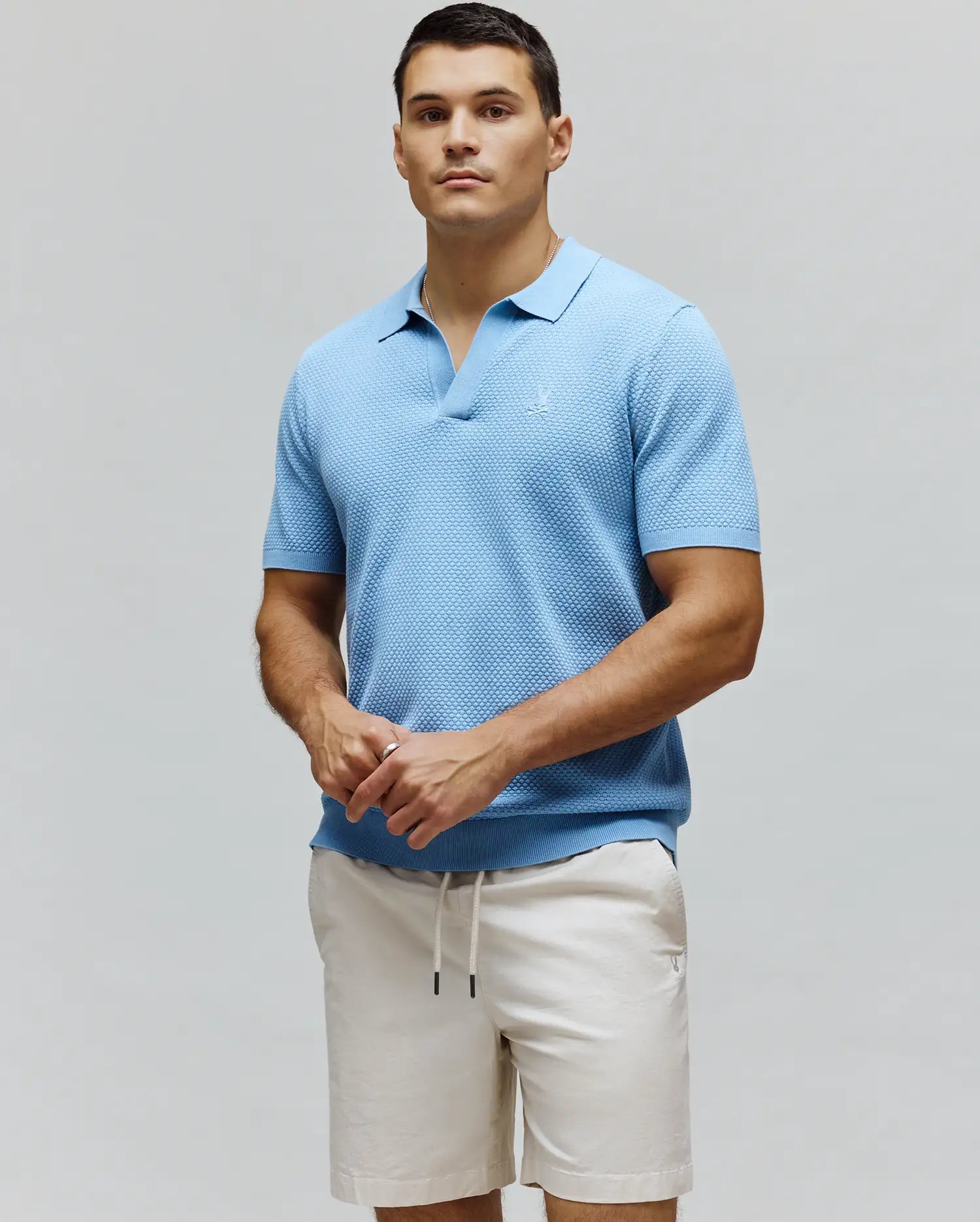 Mens Devon Knit Polo, light blue textured knit polo with an open collar, classic fit, and subtle embroidered Psycho Bunny skull logo on the left chest.