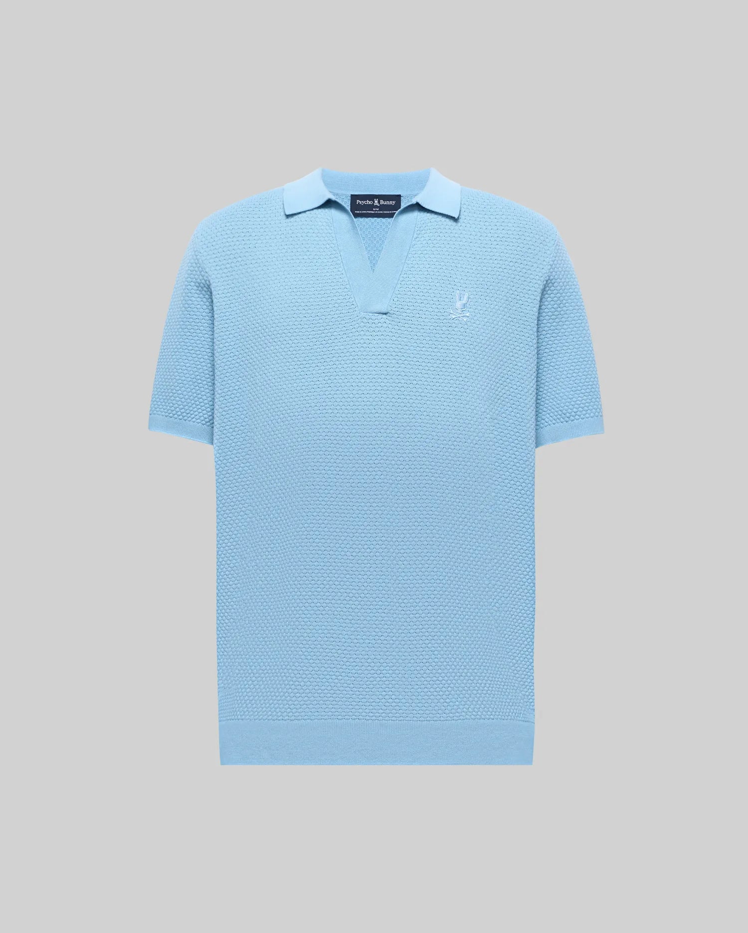 Mens Devon Knit Polo in light blue, featuring a textured knit fabric, open V-neck collar, ribbed cuffs and hem, and a small embroidered Psycho Bunny skull logo on the left chest.