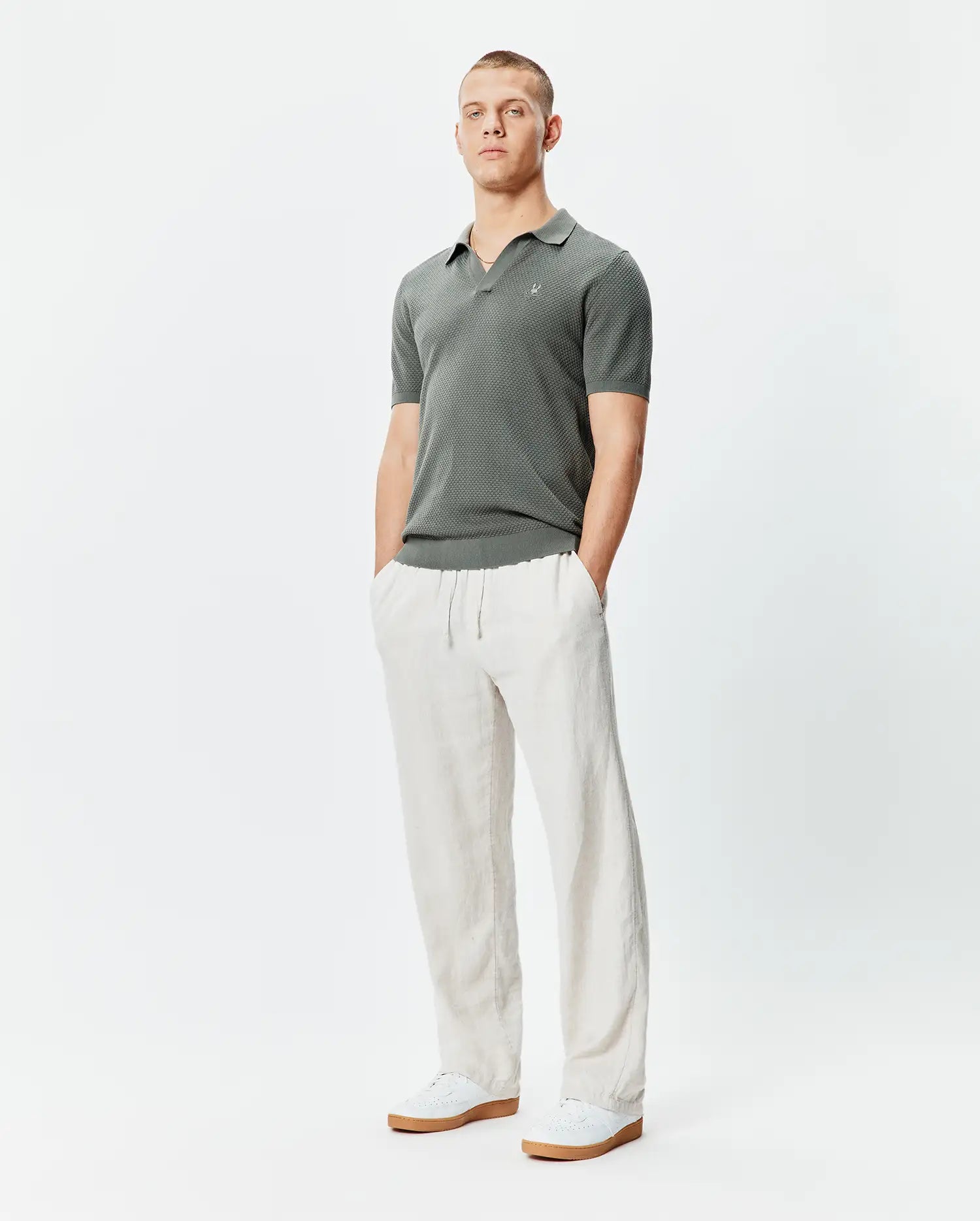 Mens Devon Knit Polo in dark green, featuring a textured knit fabric, classic fit, and a small white embroidered Psycho Bunny skull logo on the left chest.