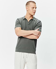 Mens Devon Knit Polo in dark green, featuring a textured knit fabric with a mini bubble pattern, open collar, ribbed cuffs and hem, and a small embroidered Psycho Bunny skull logo on the left chest.