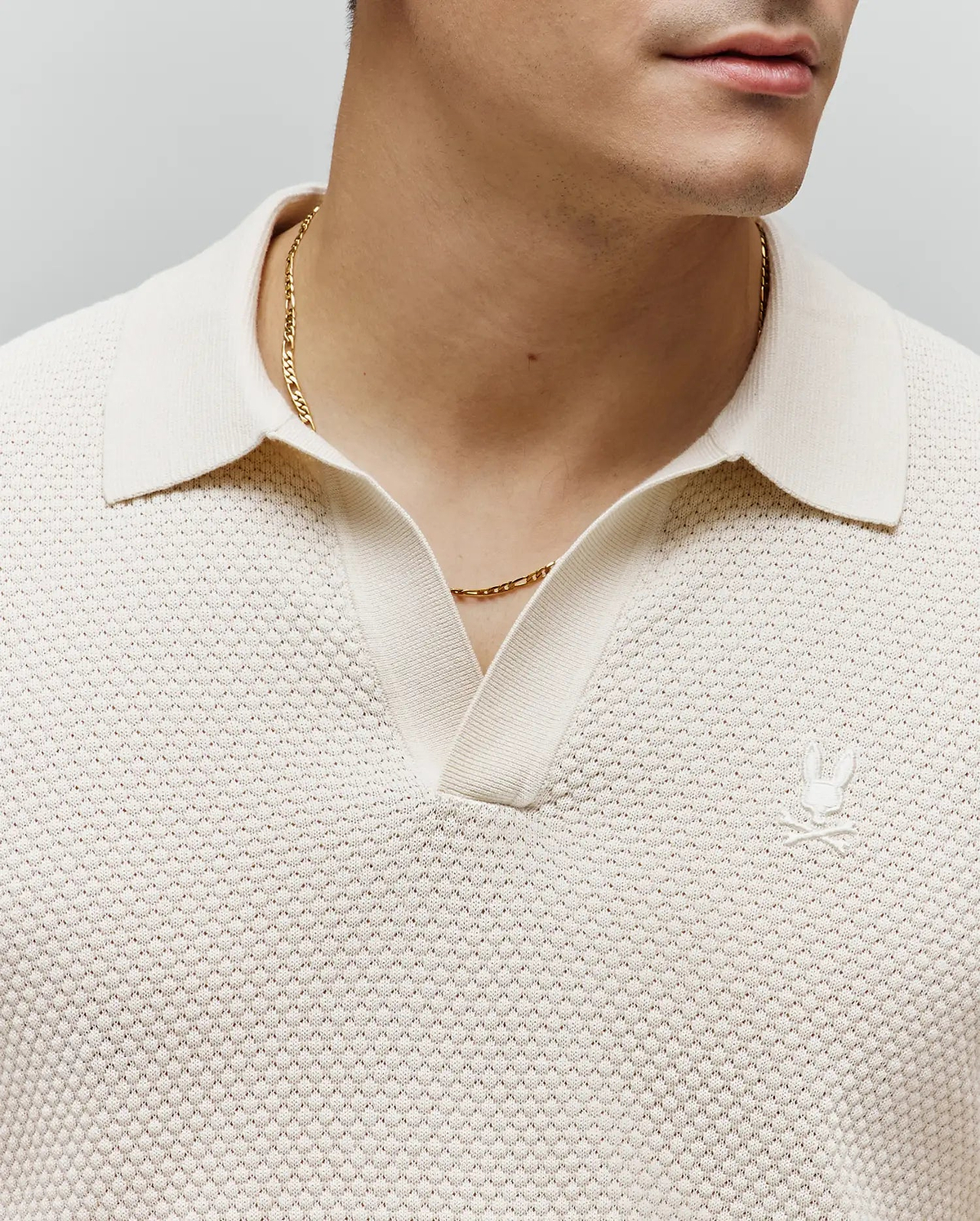 Mens Devon Knit Polo in cream, featuring a textured knit fabric, open V-neck collar, and a small embroidered cream Psycho Bunny skull logo on the left chest.