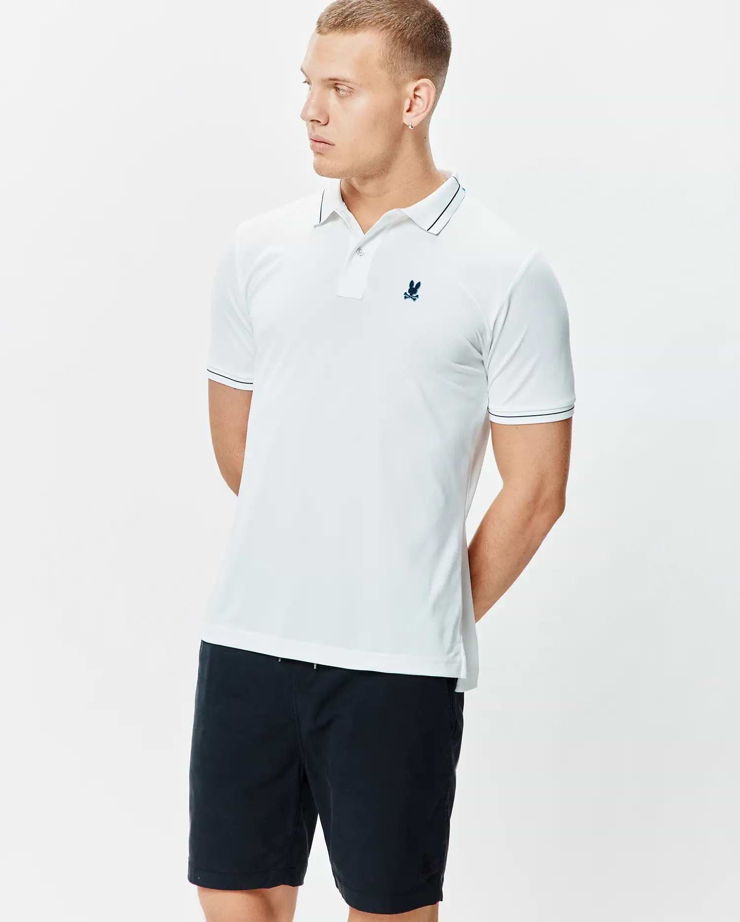 Mens Edwin Sport Polo, a classic fit white performance jersey polo with navy tipping on the collar and sleeve cuffs, featuring a small embroidered navy Psycho Bunny skull logo on the left chest.