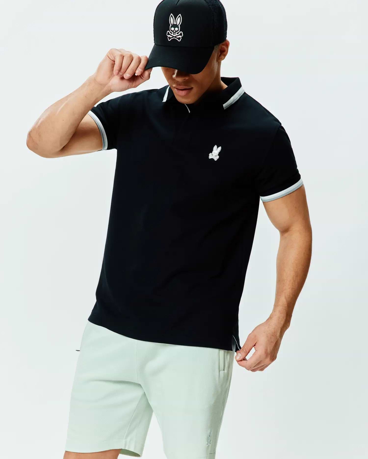 Mens Holden Pique Polo, black classic fit pique polo with white tipped collar and cuffs, featuring a small embroidered white Psycho Bunny skull logo on the left chest.