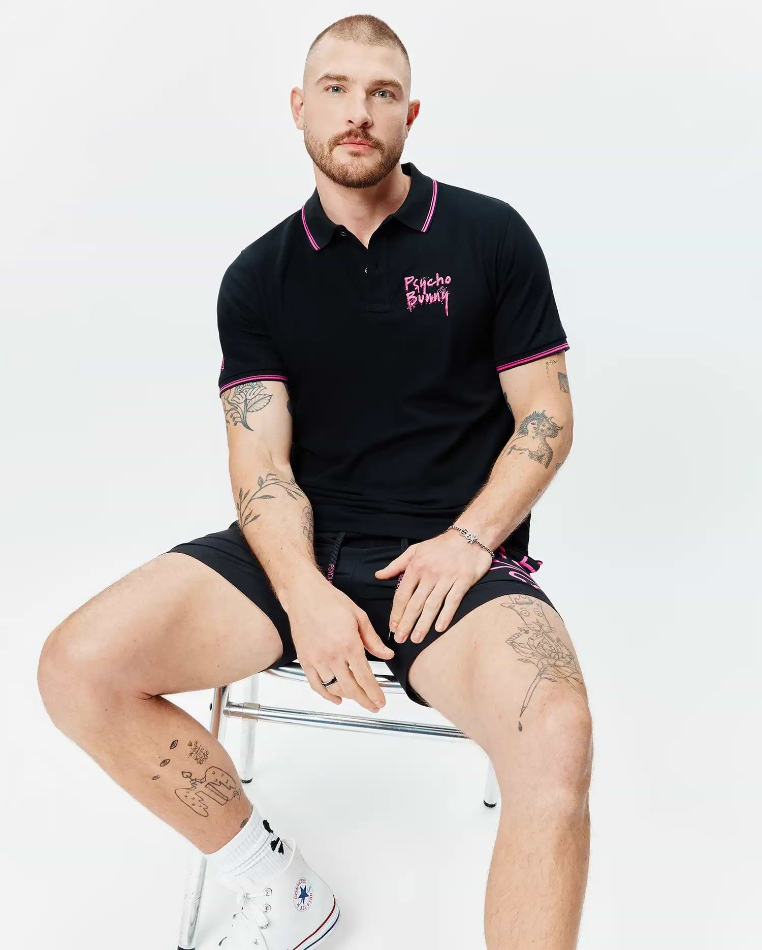 Mens Duncan Pique Polo, black with pink striped collar and sleeve cuffs, featuring an embroidered pink Psycho Bunny script logo on the left chest, in classic fit pique fabric.