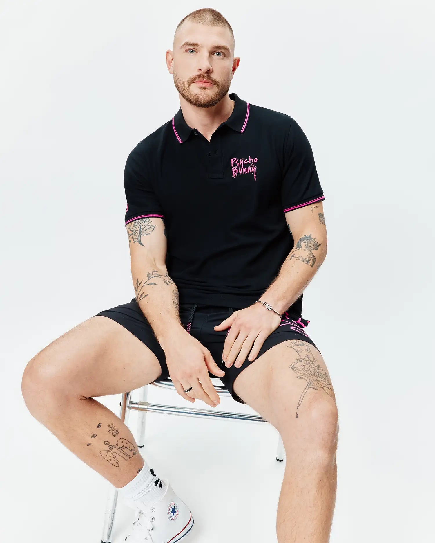 Mens Duncan Pique Polo, black with pink striped collar and sleeve cuffs, featuring an embroidered pink Psycho Bunny script logo on the left chest, in classic fit pique fabric.