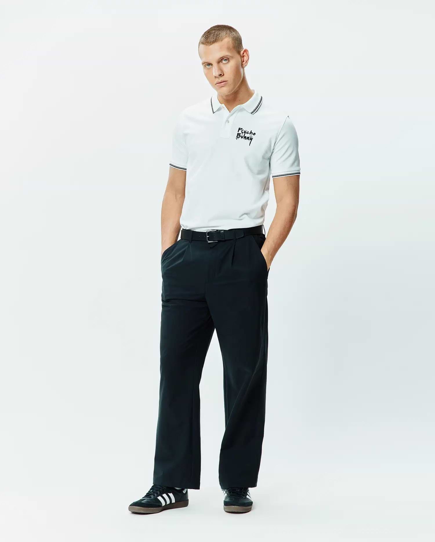 Mens Duncan Pique Polo, white pique, classic fit, with black striped collar and cuffs, featuring an embroidered black Psycho Bunny script logo on the left chest.