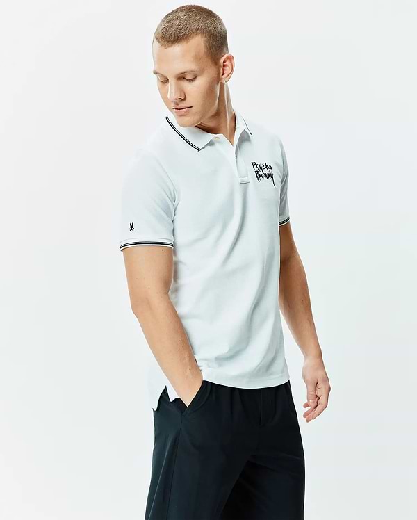 Mens Duncan Pique Polo, a light blue classic fit pique polo with black and white striped collar/cuffs, featuring a large black Psycho Bunny script chest logo and small bunny skull sleeve logo.