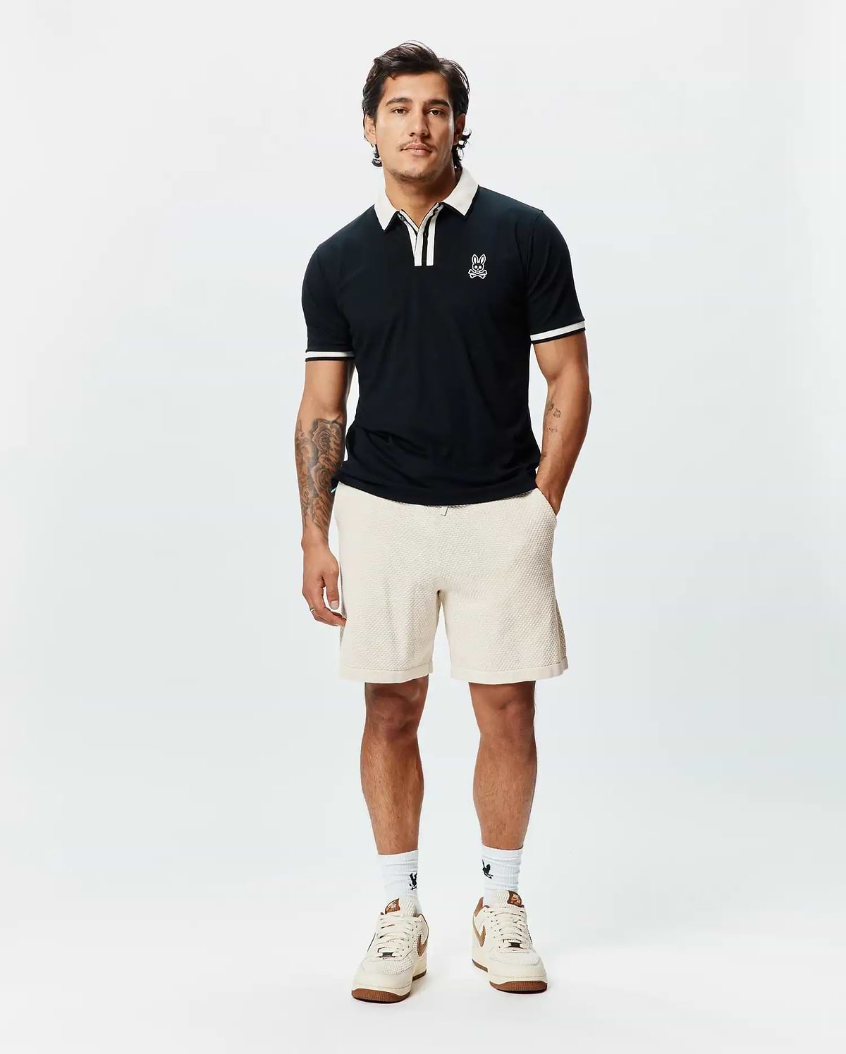 Mens Ridley Pique Polo, a classic fit black pique polo with white tipped collar and sleeve cuffs, featuring a small embroidered Psycho Bunny skull logo on the left chest. (1)