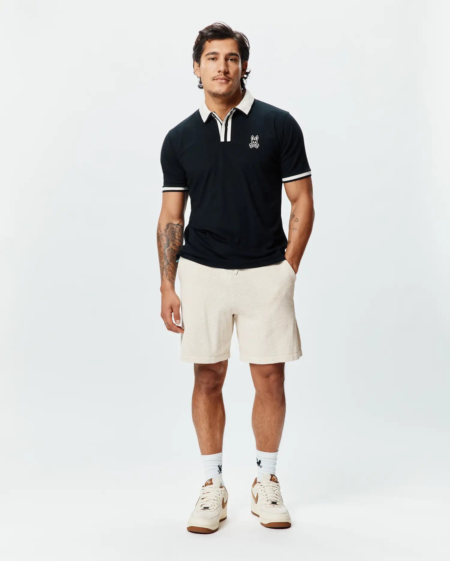 Mens Ridley Pique Polo, a classic fit black pique polo with white tipped collar and sleeve cuffs, featuring a small embroidered Psycho Bunny skull logo on the left chest. (1)
